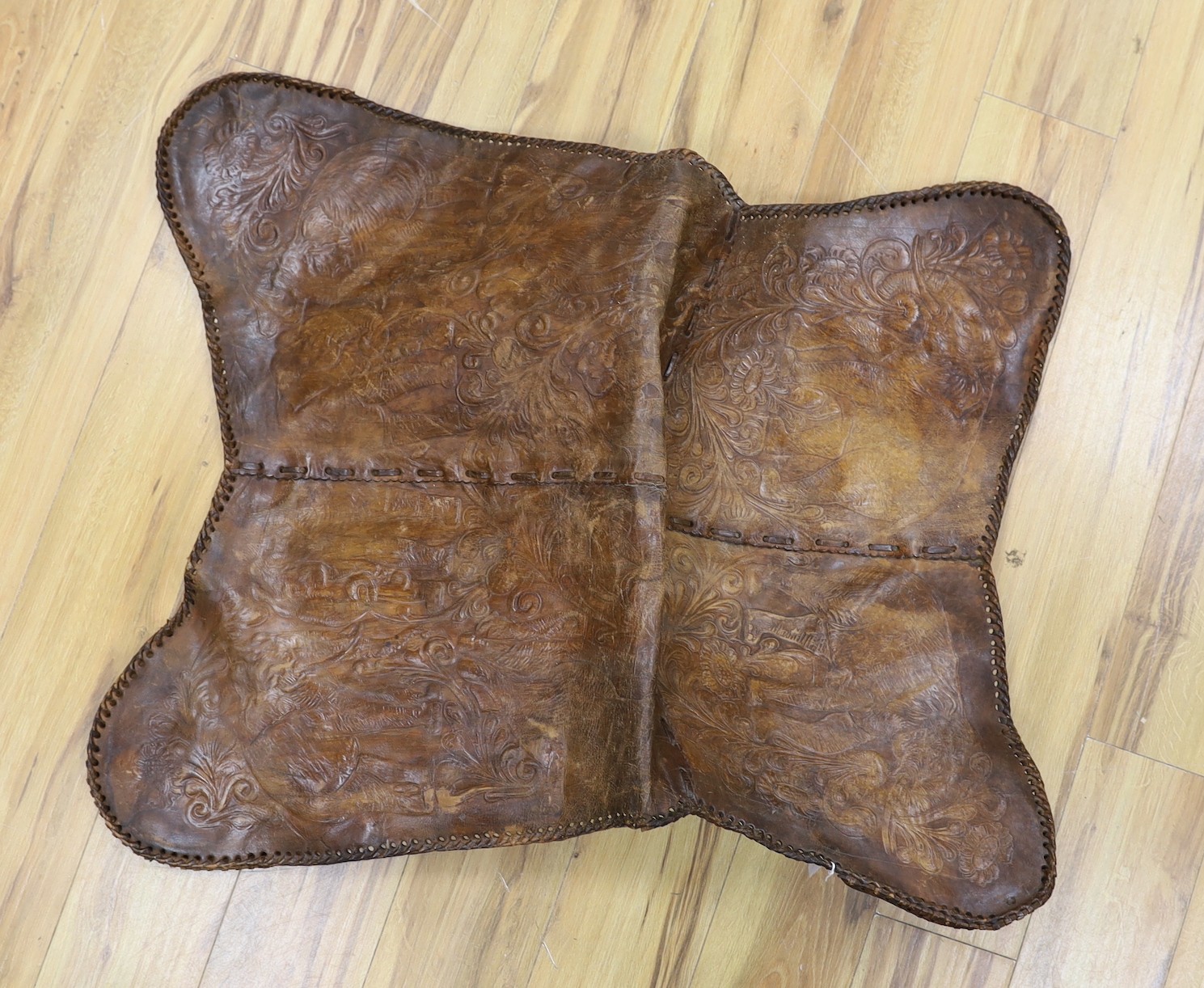 A shaped embossed leather chair seat, with leather thong edging